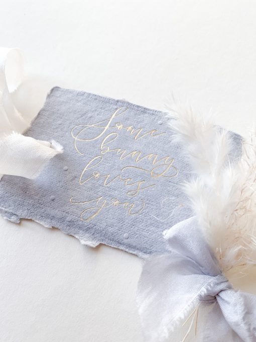 Blue gift tags with the words some bunny loves you. Gold foil on blue paper