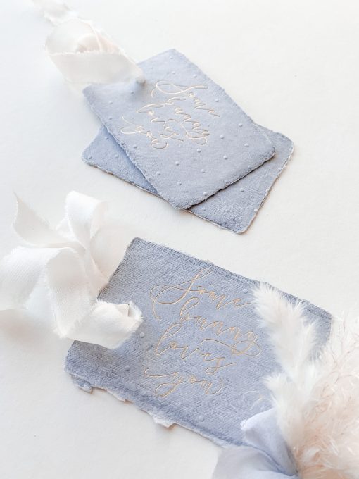 Blue gift tags with the words some bunny loves you. Gold foil on blue paper.