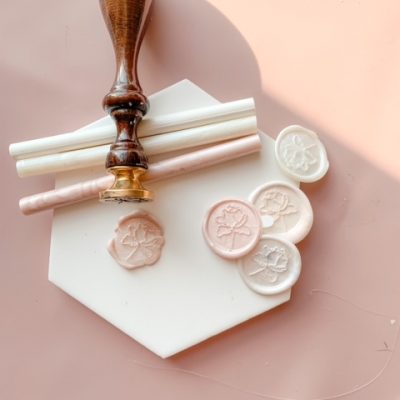 Branded wax seal stamp in different shades of ivory and pink. And showing the wooden wax seal stamp.