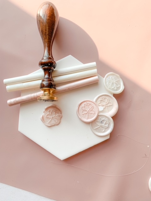Branded wax seal stamp in different shades of ivory and pink. And showing the wooden wax seal stamp.