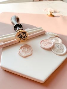 Branded wax seal stamp in different shades of ivory and pink. And showing the brass head of the stamp.